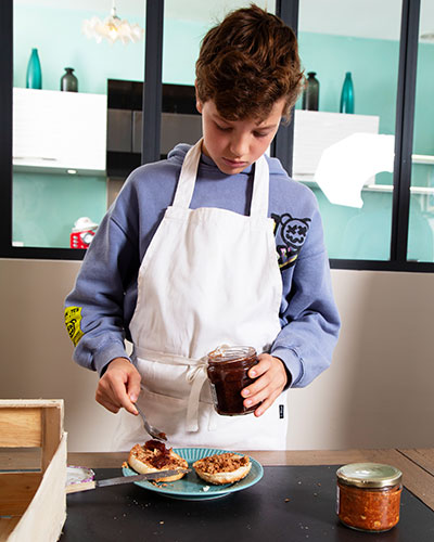 Recette de Noël : les burgers de fête de Kimi. Tartiner l’intérieur des pains avec la terrine. Ajouter de la confiture de figue.
