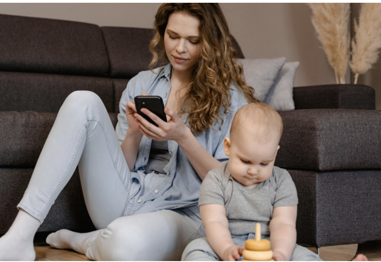 Une femme sur son téléphone avec son enfant