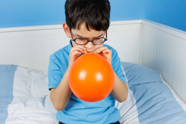 Photo d'un garçon soufflant dans un ballon.