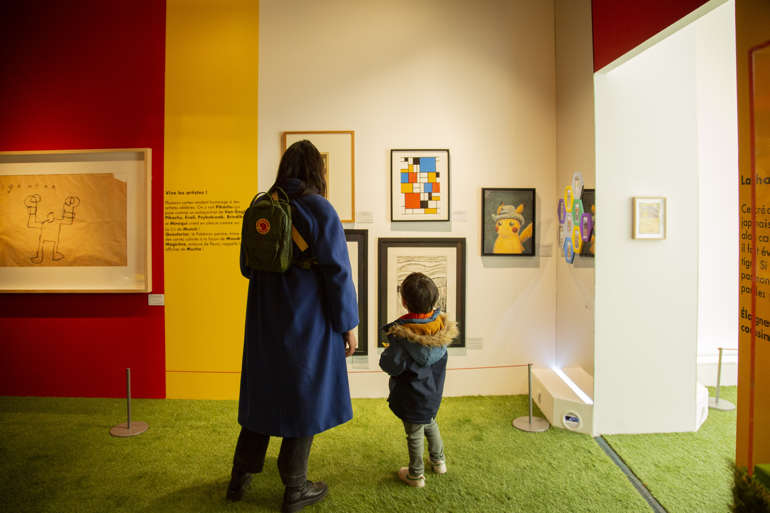 Un enfant et un adulte regardent des tableaux.